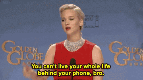 a woman in a red dress stands in front of a microphone and says you can 't live your whole life behind your phone