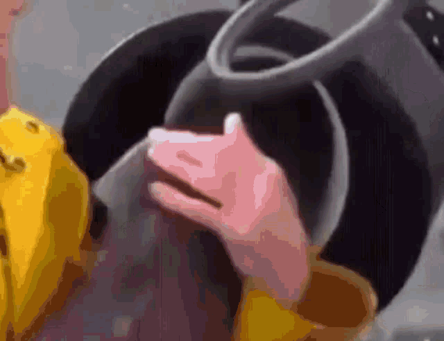 a person wearing a yellow jacket is holding a gray object in their hand .