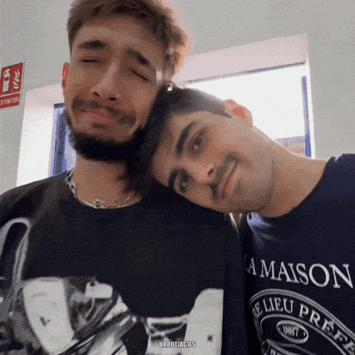 two men are posing for a picture and one of them is wearing a maison t-shirt