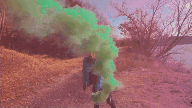 a man in a blue jacket is holding green smoke