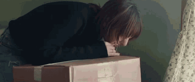 a woman is laying on top of a cardboard box in a room .