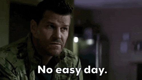 a man in a military uniform is sitting in a dark room and says `` no easy day '' .