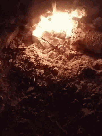 a fire is coming out of the ground in a cave at night .
