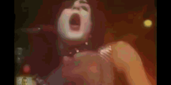 a close up of a woman 's face with her mouth open in a dark room .
