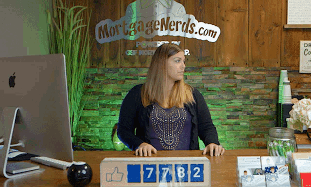 a woman sits at a desk with a sign that says mortgage nerds.com