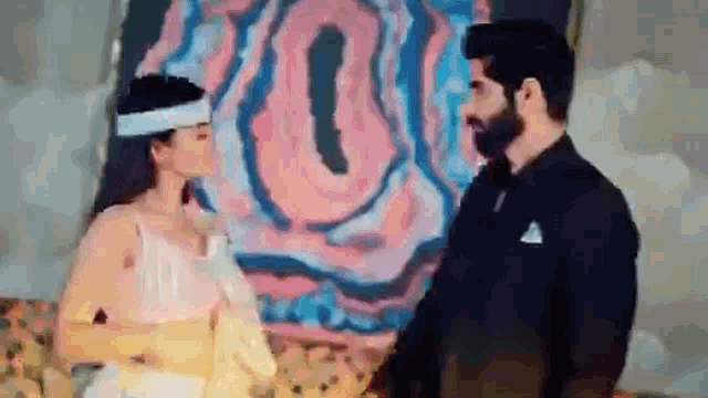 a man and a woman are standing in front of a painting .