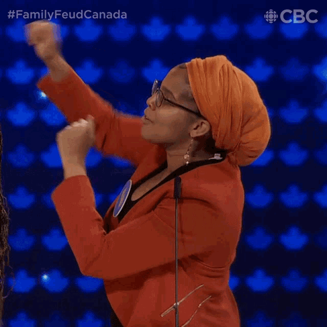 a woman wearing an orange turban and glasses stands in front of a microphone with a cbs logo in the corner