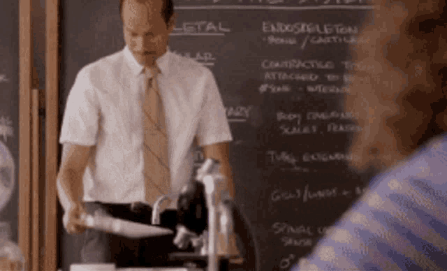 a man is standing in front of a chalkboard that says ' endoskeleton ' on it