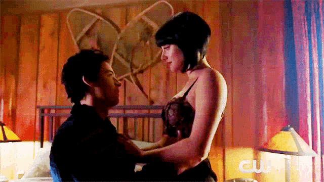 a man and a woman are kissing in a bedroom with a cw logo on the bottom right