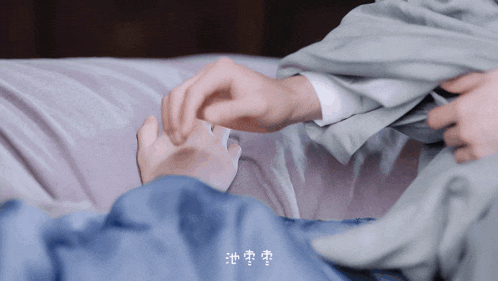 a person laying on a bed holding another person 's hand with chinese writing above them