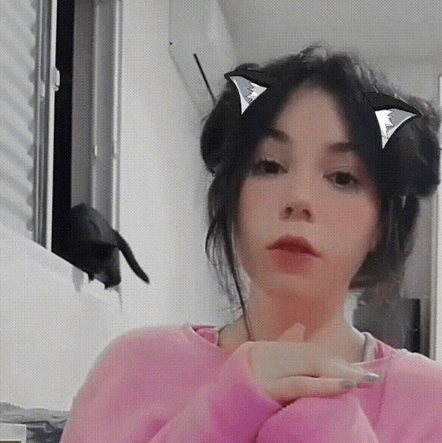 a woman wearing a pink sweater and cat ears on her head