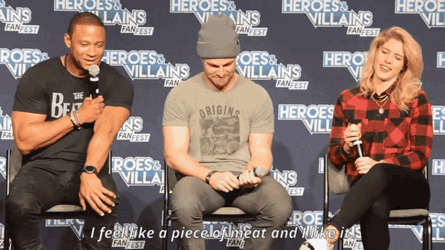 a group of people sitting in front of a heroes and villains fanfest banner