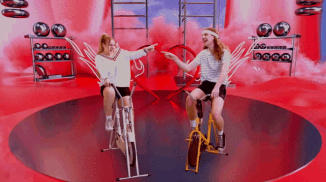 two women are riding exercise bikes in a circle