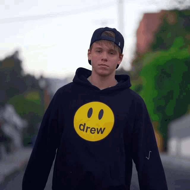 a boy wearing a black hoodie with a yellow drew face on it