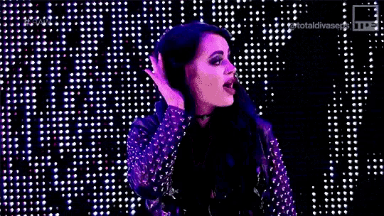 a woman is holding her hair in front of a wall of lights .