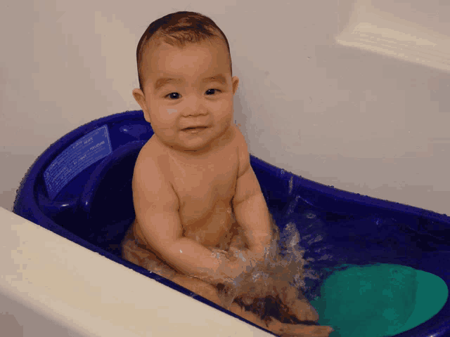 a baby is taking a bath in a bathtub that has a sticker on it that says ' warning ' on it