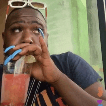 a man with long blue nails is drinking a drink from a bottle .