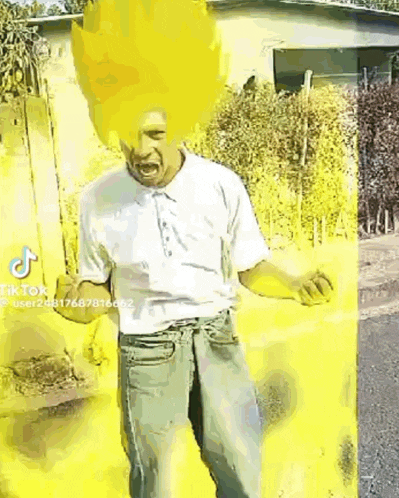 a man in a white shirt and jeans is standing in front of a yellow wall with a yellow hairdo .