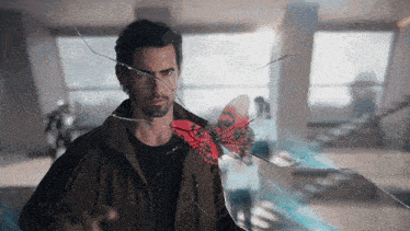 a man is holding a red butterfly in front of a broken glass