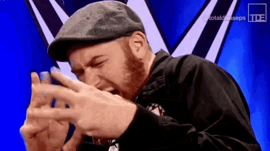 a man with a beard wearing a hat and a black jacket is making a funny face .