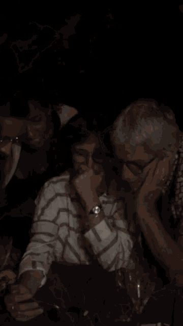 a man wearing glasses is covering his mouth with his hand