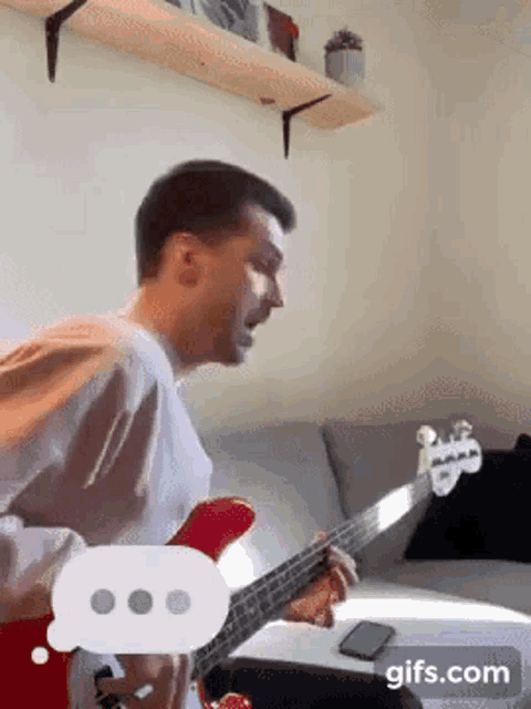 a man is playing a red guitar in a living room