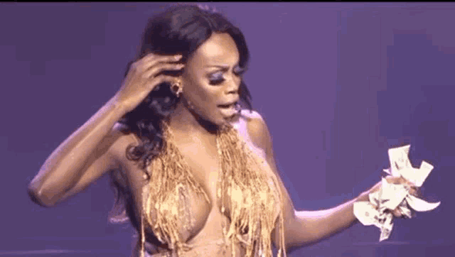 a woman in a gold dress is holding a bunch of money in her hands .
