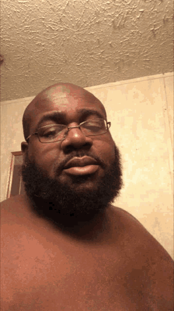 a shirtless man with a beard wearing glasses