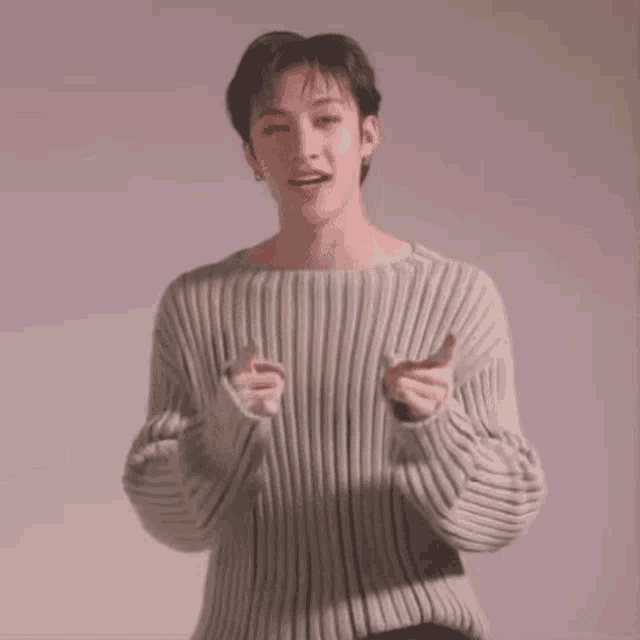 a young man in a sweater is clapping his hands together .