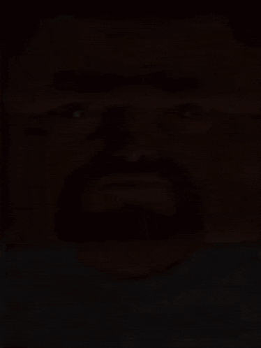 a close up of a man 's face with a beard wearing a blue shirt