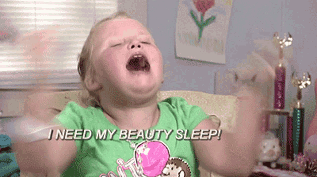 a little girl is sitting on a couch with her mouth open and the words i need my beauty sleep above her