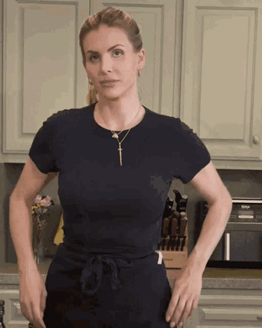 a woman in a black shirt is standing in front of a ninja oven