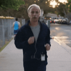 a man in a blue jacket is running down the sidewalk