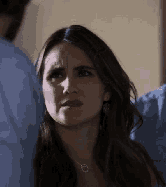 a woman wearing a necklace and earrings is making a silly face