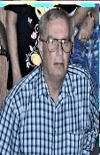a man wearing glasses and a plaid shirt is sitting at a table with other people .