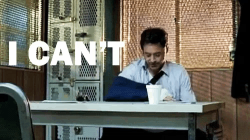 a man with a broken arm sits at a desk with the words " i can 't " written above him
