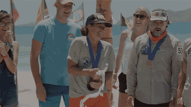 a group of people are standing on a beach and one of them has the number 53 on their shirt