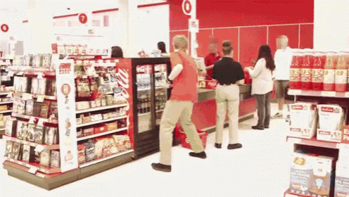 a man in a red shirt is dancing in front of a target sign