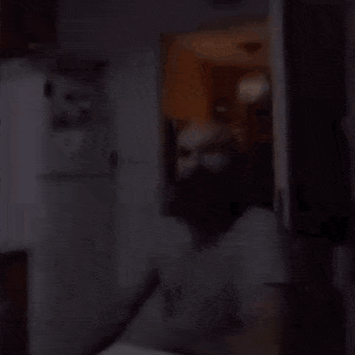 a man with a beard is sitting in front of a refrigerator .