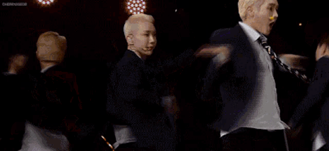 a group of men in suits and ties are dancing on a stage