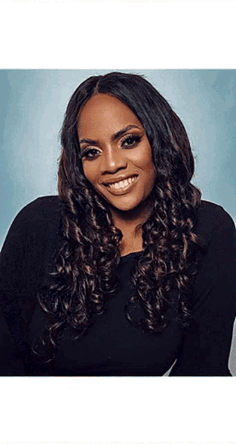 a woman with long curly hair wearing a black shirt is smiling