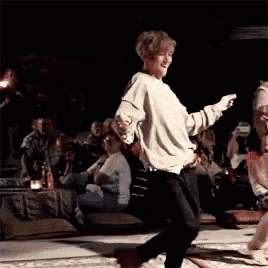 a woman is dancing on a stage in front of a crowd .