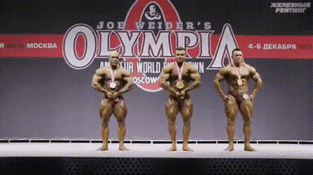 three bodybuilders standing on a stage in front of a joe weider 's olympia logo