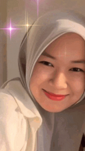 a woman wearing a hijab is smiling with a pink star in the background