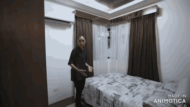 a woman is standing next to a bed in a bedroom with a sign above it that says bedroom # 2 .