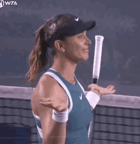 a woman is holding a tennis racquet on a court with the wta logo in the corner