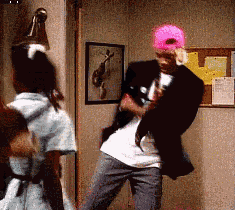a man wearing a pink hat is dancing in a room with a nurse .