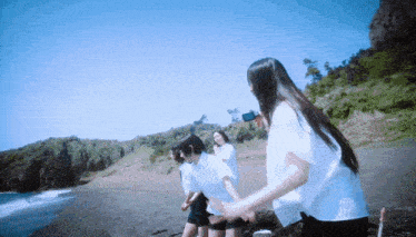 a group of girls standing on a beach with a blue sky in the background