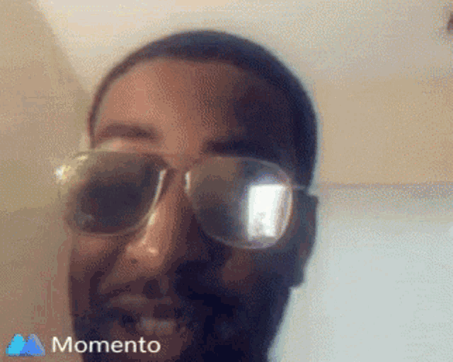 a man wearing sunglasses is smiling in a momento app