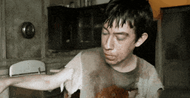 a man with a dirty shirt on is standing in a room